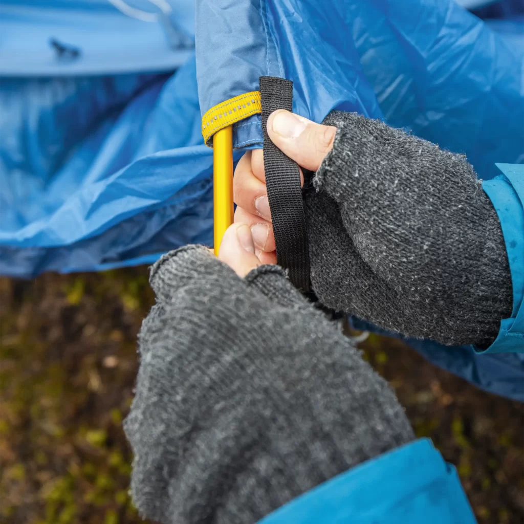 Kädet laittavat telttakaaria paikalleen