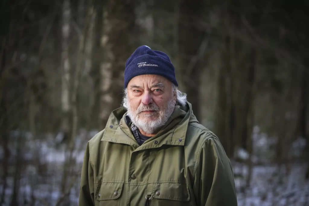 Mies katsoo kameraan talvisessa metsässä