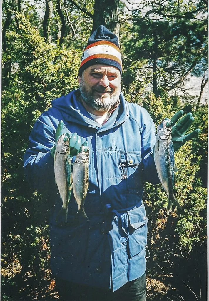 Mies sinisessä takissa pitelee kaloja