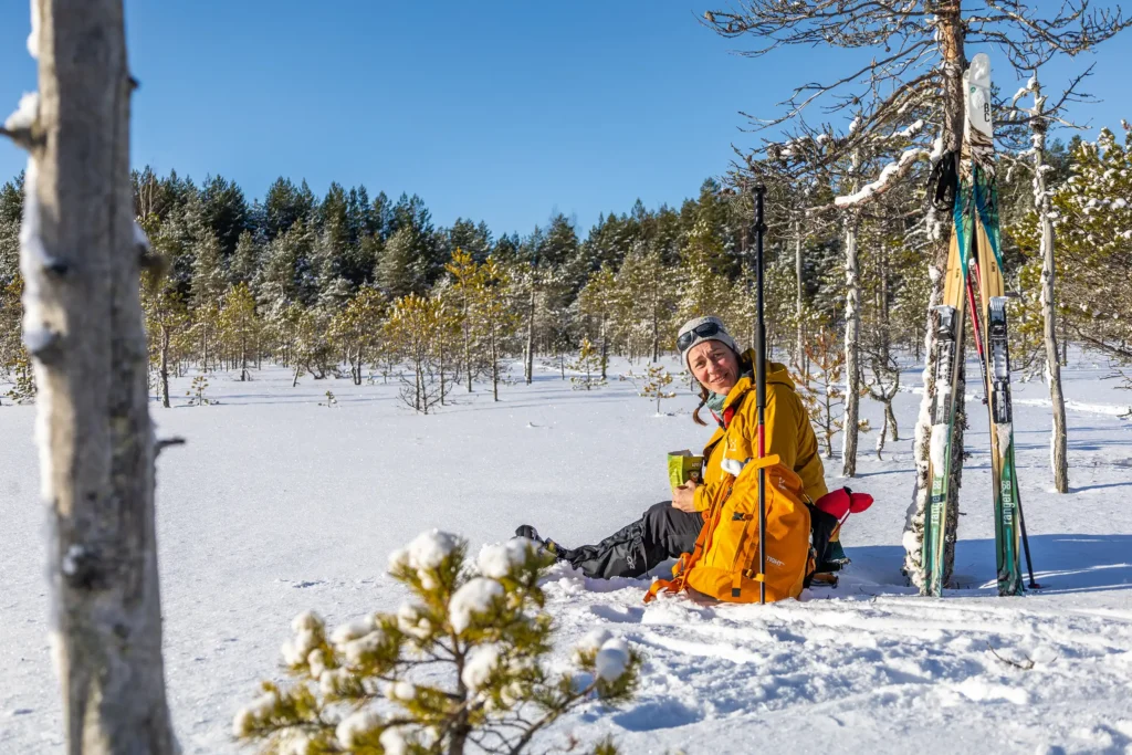 Nainen istuu lumisessa maassa lounaalla Leivonmäen kansallispuistossa